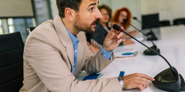 Man speaking into a conference microphone.