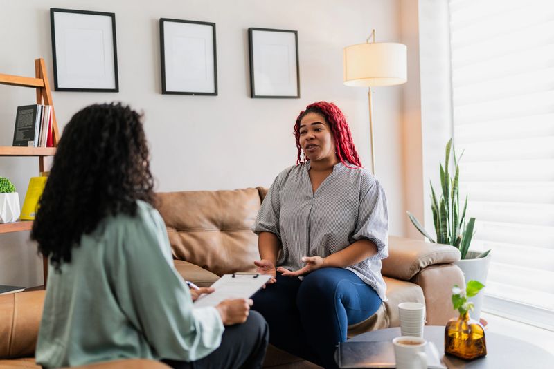Mid adult patient woman talking with psychotherapist during therapy session at clinic