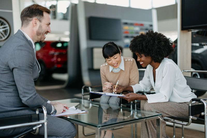 Customer signing car purchase documents with a saleswoman, depicting the business aspect of buying a car