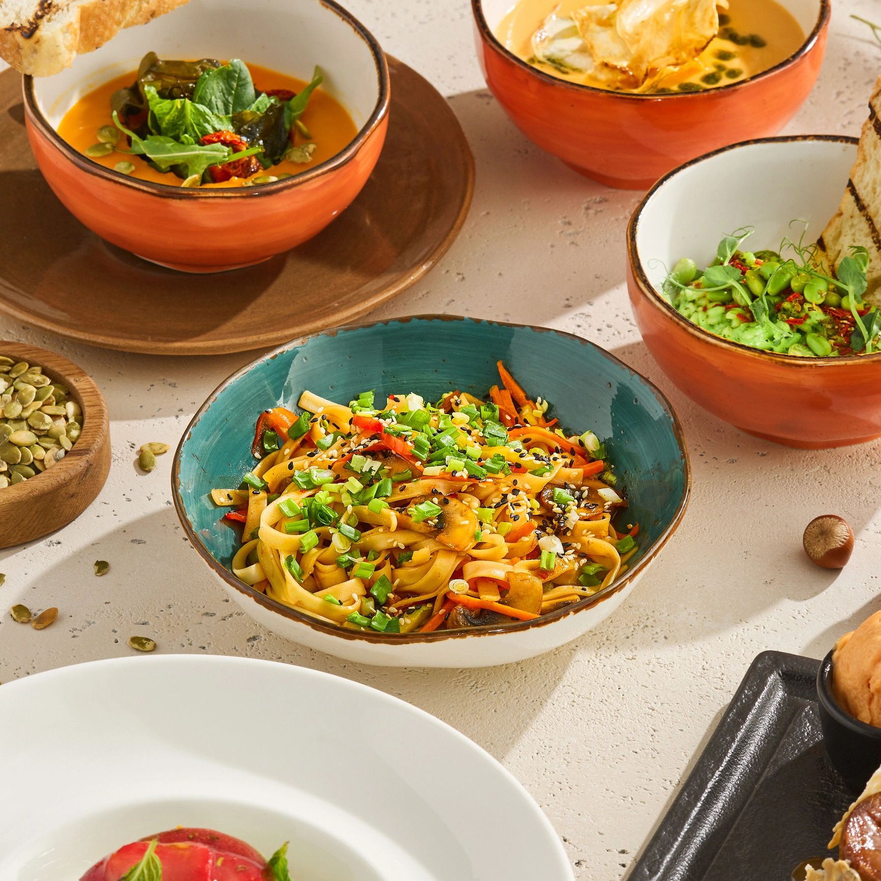 Colorful Asian noodle dish garnished with green onions and sesame seeds in a ceramic bowl.