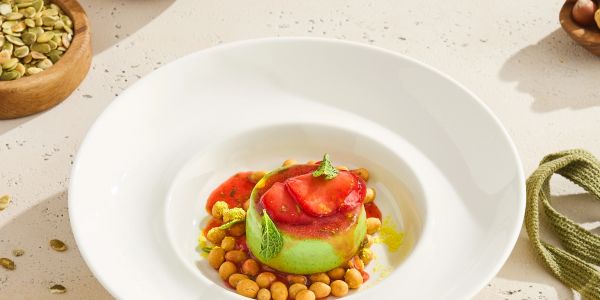 Elegant dish with green mousse, chickpeas, and red sauce served in a white bowl.