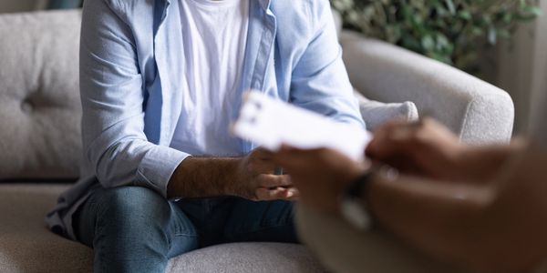 Two people sitting opposite each other on sofas talking. 