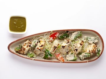 Grilled paneer with bell peppers and green chutney on the side.