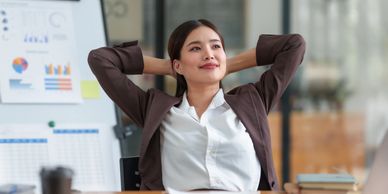 Woman relaxing in office chair with hands behind head.