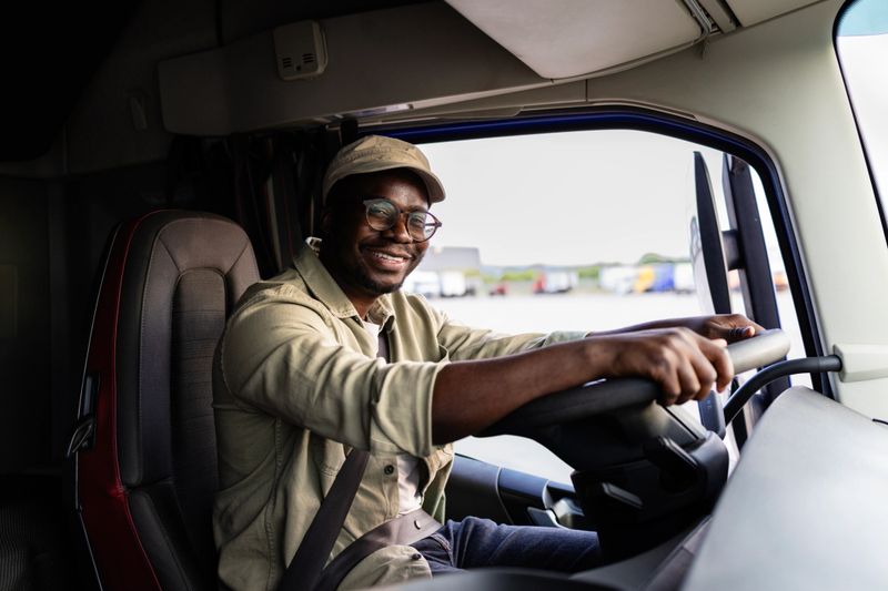 Professional driver sitting in the cabin and driving truck.