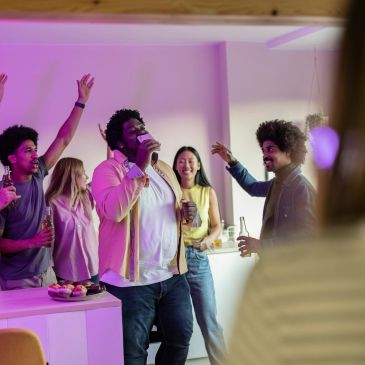Group of friends enjoying a lively karaoke night with drinks and cheers.