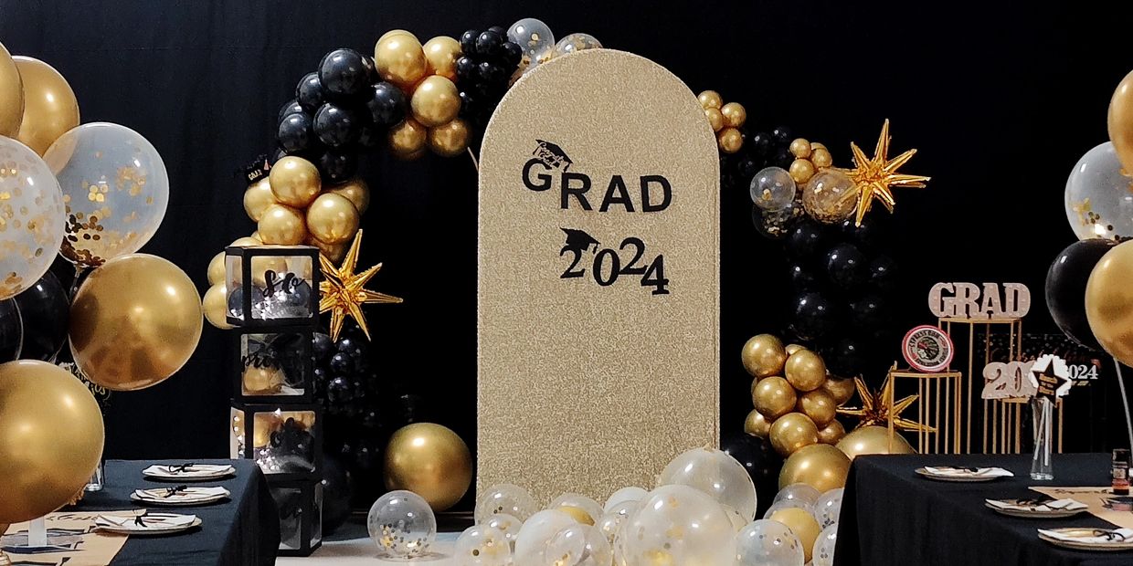 A gold and black themed 2024 graduation party setup with balloons and decorations.