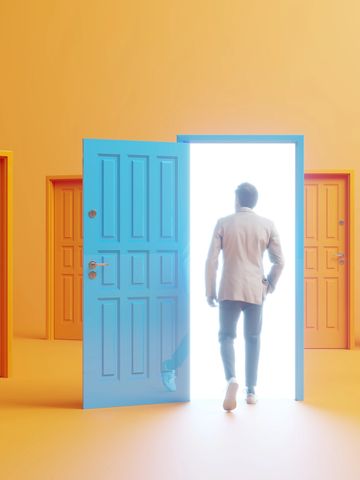 Man in suit stepping through an open glowing blue door among closed orange doors.