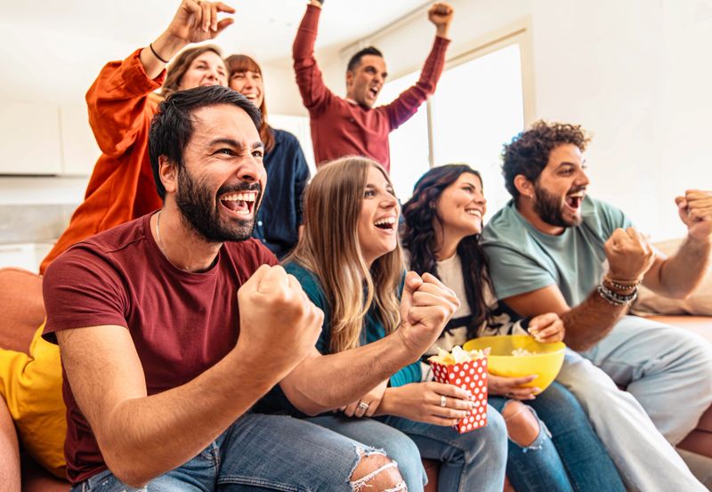 Happy friends watching soccer world cup on television at home