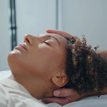 Woman peacefully resting with eyes closed and hands behind head.