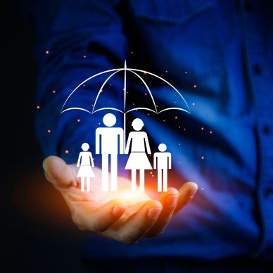 Hand protecting family under umbrella symbolizing insurance.