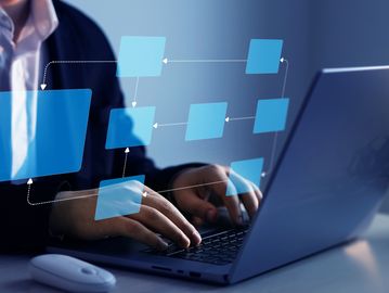 Person working on laptop with digital flowchart overlay.