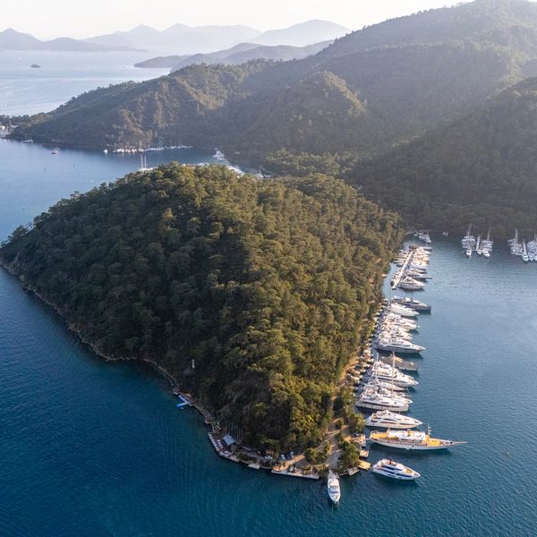 Mavi sularla çevrili, yemyeşil ormanlarla kaplı bir yarımada ve marinalarda demirlemiş tekneler.