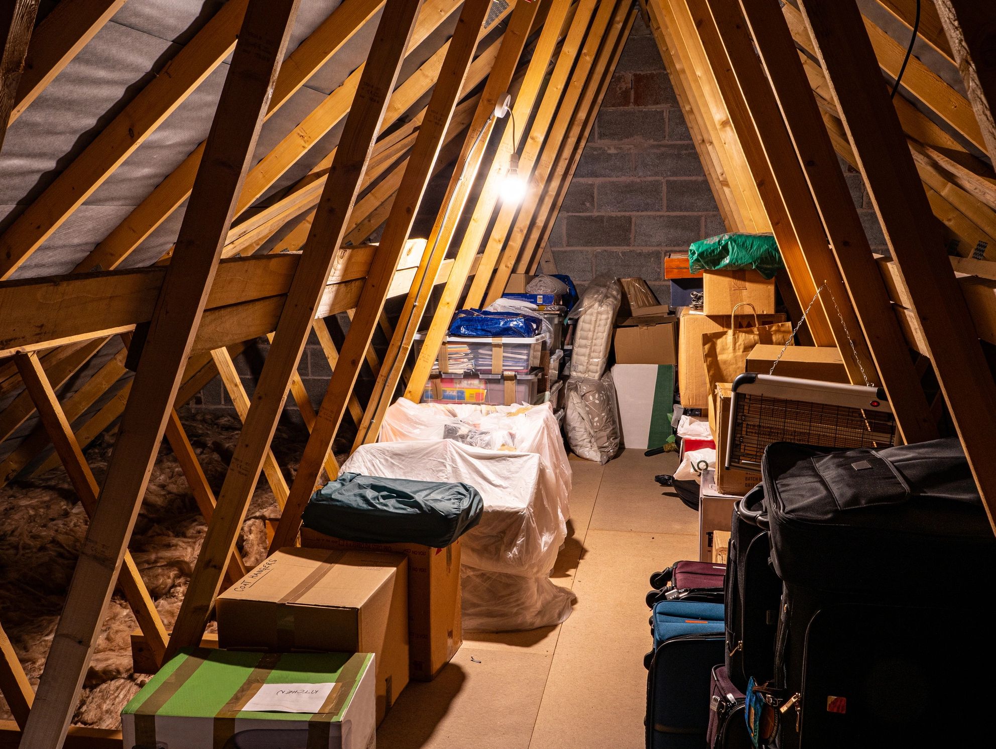 Cluttered attic with storage boxes and suitcases.