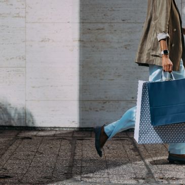 Person walking with shopping bags on a sunny day.