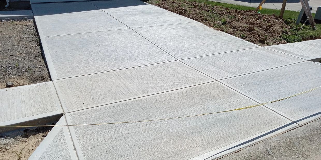 Large residential concrete driveway installation with crisp edges and seamless entry to the garage.