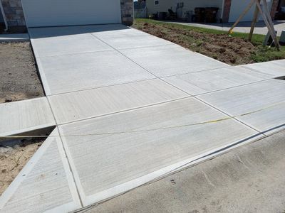 Freshly poured concrete driveway and sidewalk in a residential area.