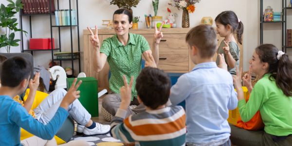 Teacher and kids counting fingers and playing in a classroom.