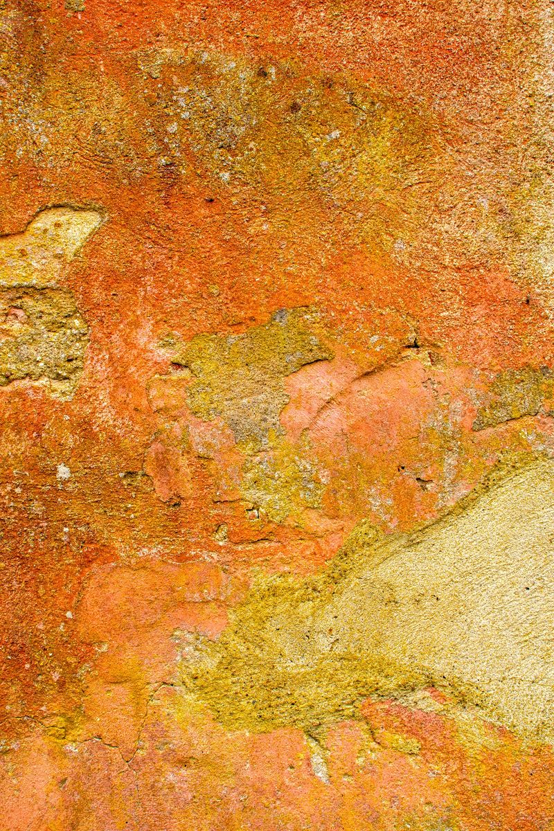 Damaged  orange wall in closeup with peeling paint and cracks
