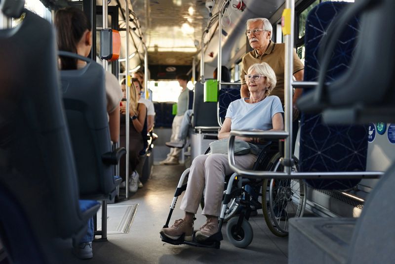 Disabled senior woman in a wheelchair and her husband traveling by a bus.