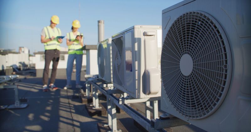Installation repair and maintenance process of an AC unit fan on top of a building roof. Technicians at work preparing and inspecting the cooling system