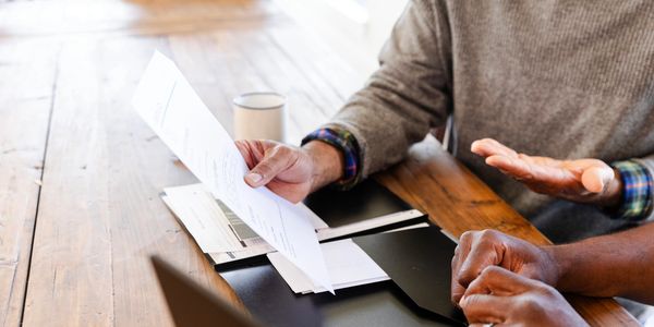 Two people discussing documents at a wooden table.