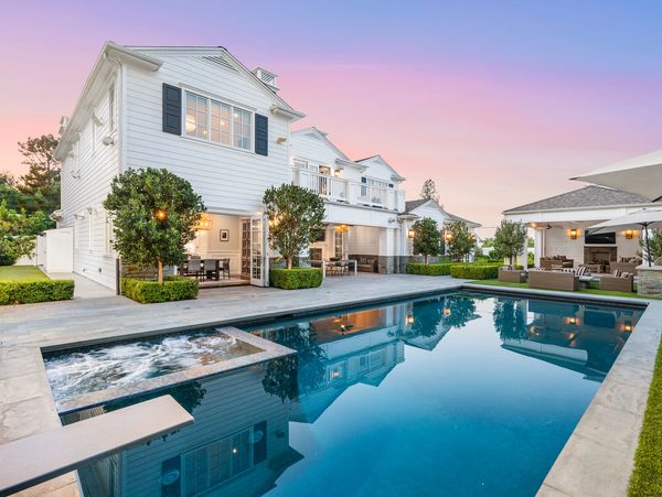 Luxurious white house with a pool and outdoor seating area at sunset.