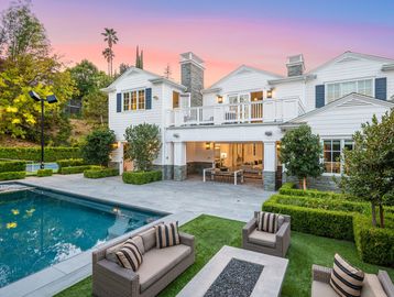 Luxurious house with pool and outdoor seating at sunset.