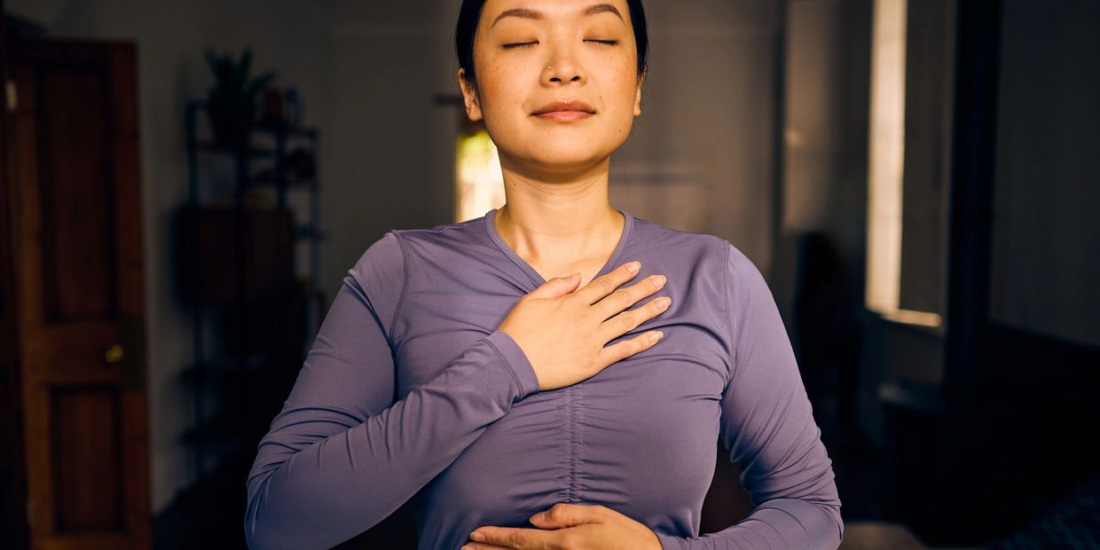 Woman practicing mindfulness with hands on chest and abdomen.