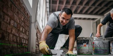 Skilled contractor using a laser level to install floor tiles during a home renovation.