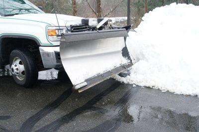 Snow plow attached to a truck clearing snow.