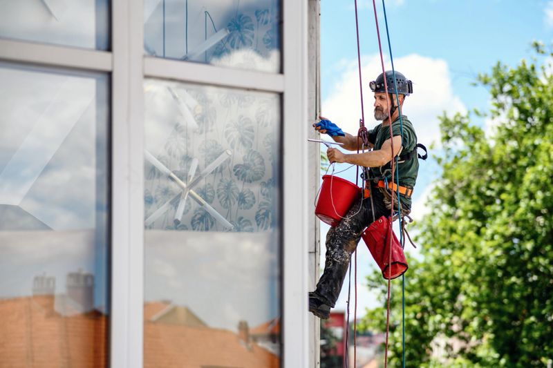 Worker cleaning windows service on high rise building. Worker cleaning glass curtain wall. Special job. Small business.