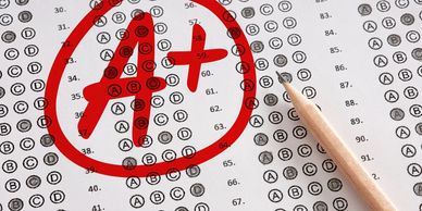 A multiple-choice test sheet with a red A+ grade and pencil.
