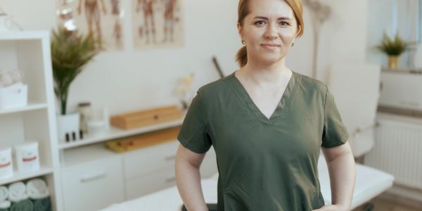 Mulher sorridente em uniforme verde em consultório.