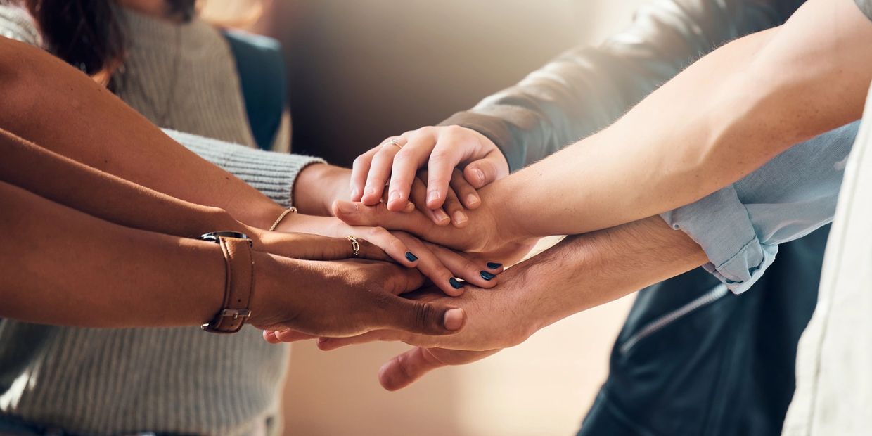 A group of people stacking their hands together in unity.