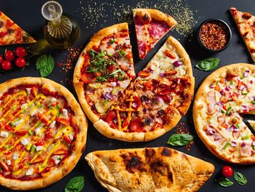 Delicious assorted pizzas and a calzone on a table.