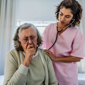 Nurse checking elderly woman's breathing with stethoscope.
