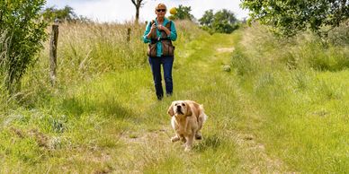 Woman playing fetch with dog in a grassy park.