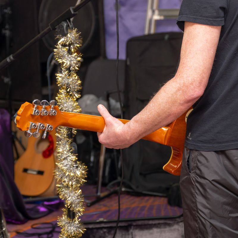 A guitarist plays the guitar at the rehearsal. Rear view