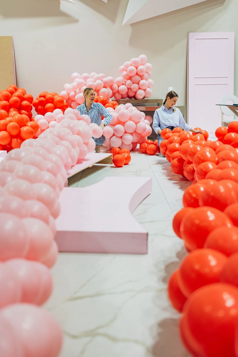 Two smiling event organizers decorated the restaurant's hall for the celebration, making a balloon arch