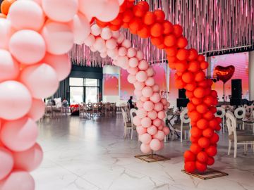 Red and pink balloon arches in a decorated event space.