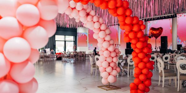 Pink and red balloon arches in a decorated event space.