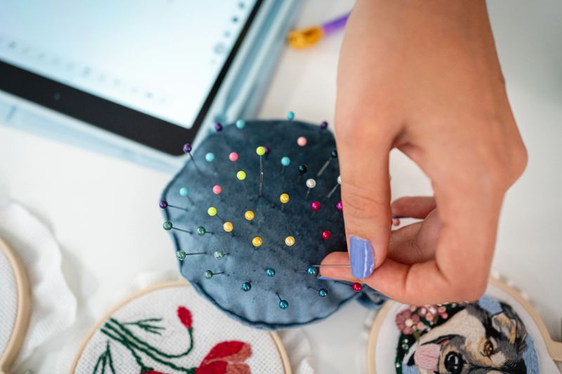 Close-up shot of unrecognizable female seamstress picking up needle, hand embroidery