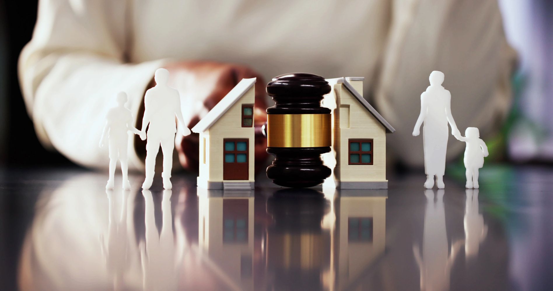 Miniature family figures, houses, and a judge's gavel symbolizing family law and property disputes.