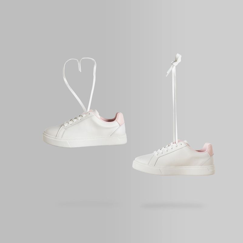 A Pair of white womens sneakers flying in the air