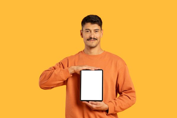 Man in orange sweater holding blank tablet.