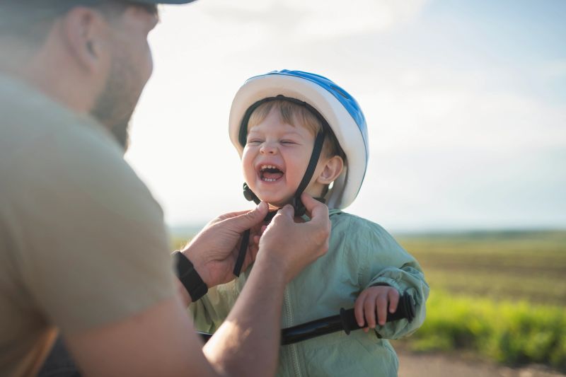 Father adjusting his little boy's helmet,preparing him for a bicycle ride.