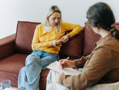 A woman in a yellow sweater looks anxious during a therapy session.