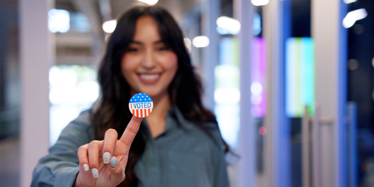 Woman proudly shows an "I Voted" sticker on her finger.