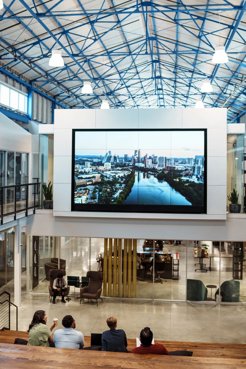 Rear view of a diverse group of young professionals sitting in the lobby of a modern office while having a casual meeting.